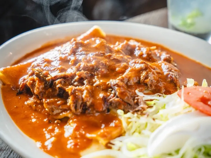 Enchiladas rancheras under a red ranchera sauce